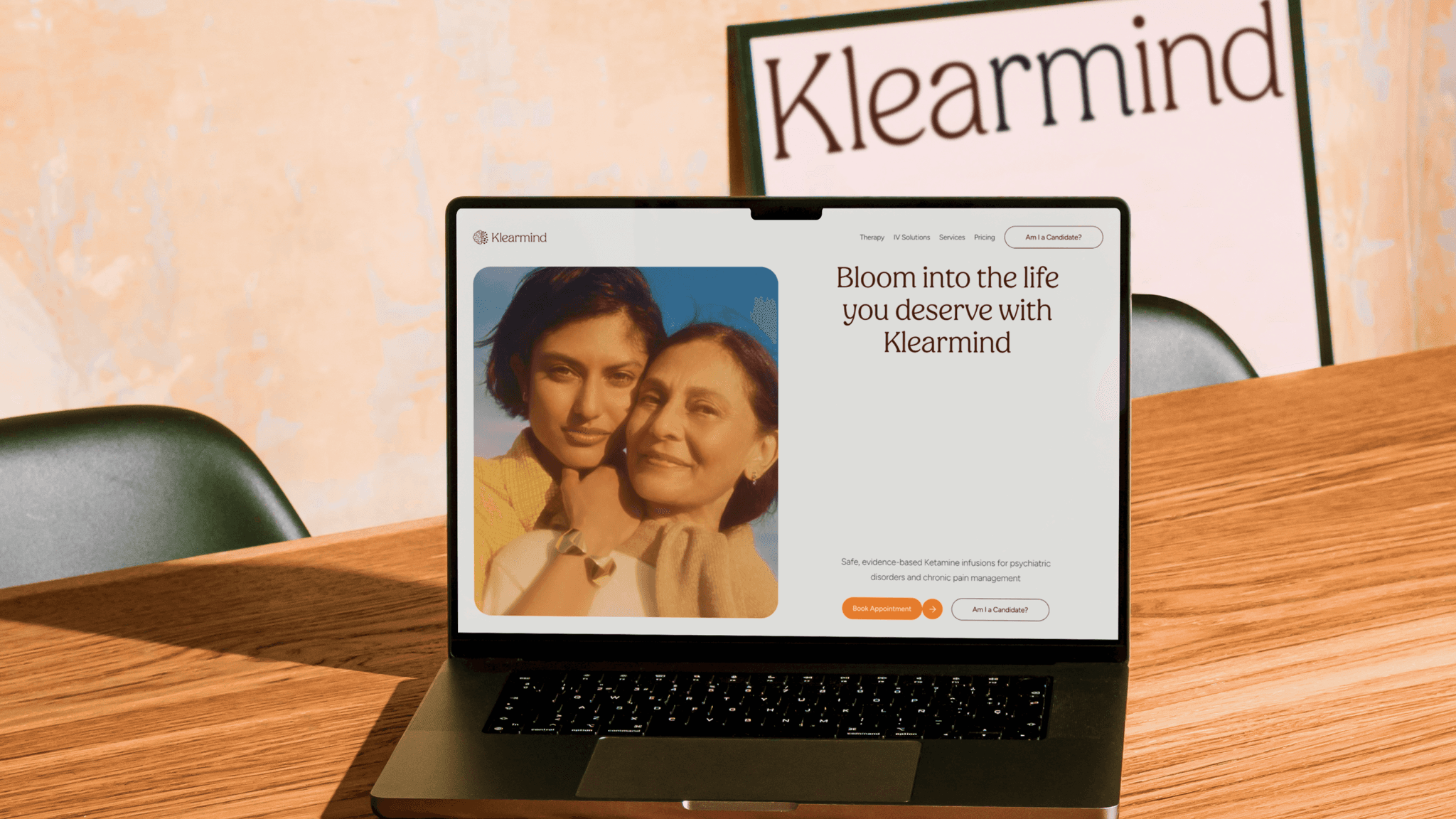Klearmind website on a laptop at a desk, with the line "Bloom into the life you deserve with Klearmind"